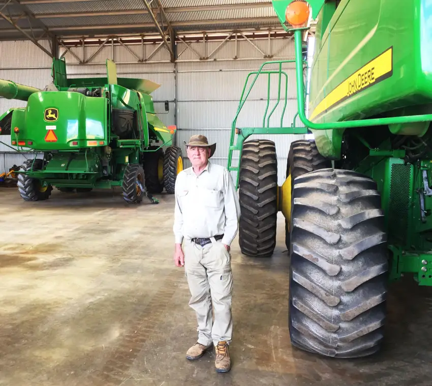 Grower standing in farm shed next to John Deere farming equipment