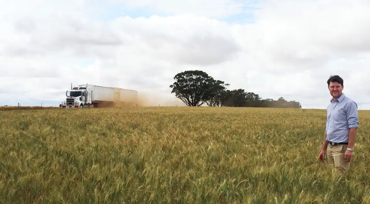 Photo of Peter Brennan standing in a field with truck passing by
